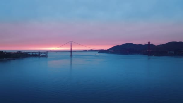 Letecký snímek závěsný most s kinematografickým krásným růžovým západem slunce v oblačný den — Stock video