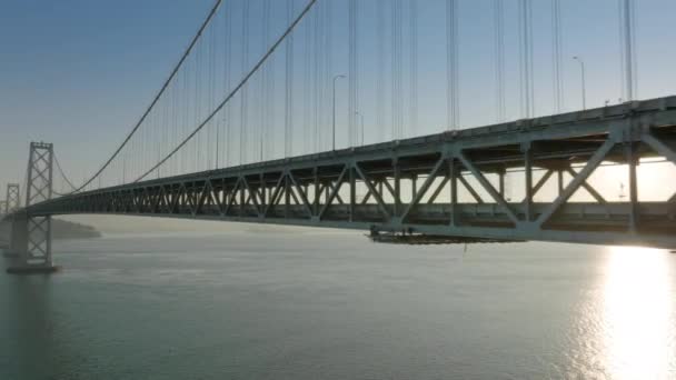 Cinematic aerial bright sun rays shining through bridge construction at sunrise — ストック動画