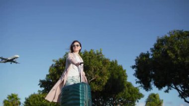 Ağır çekimde bavullu kadın iniş uçağı RED ile güneşli günbatımının tadını çıkarıyor.