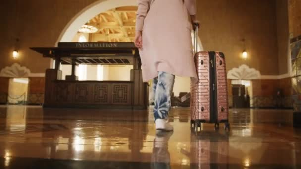 Жінка в довгих випадкових кардиганах біле взуття з багажем, що йде по залізничній станції — стокове відео