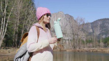 Kadınlar su içer, güneşli bir günde dağ parkında dinlenirler, Yosemite.