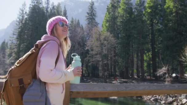Smiling woman drinks water from hiking bottle on adventure in Yosemite Valley 6K — стоковое видео