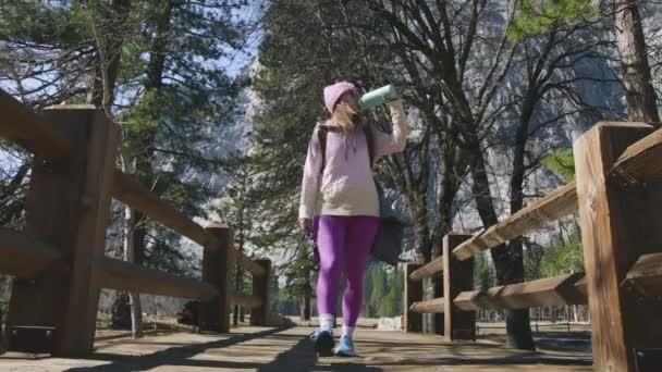 Mädchen in Fitness-Leggings trinkt während Wanderpause Yosemite aus Sportflasche — Stockvideo