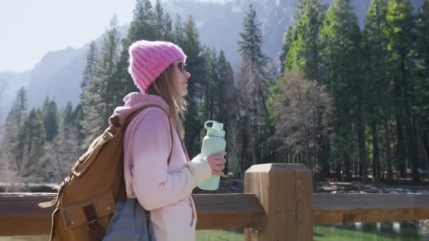 Mujer joven y saludable con botella de agua dulce pura del glaciar del río de montaña — Vídeos de Stock