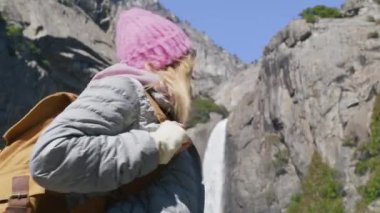 Yosemite şelalesine bakan, turist çantalı, heyecanlı genç yürüyüşçü kadın.