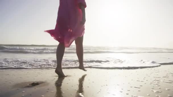 Femme en belle robe rose ondulée au coucher du soleil, femme pieds marchant sur la plage 6K — Video