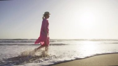 Mutlu romantik kadın plajda gün batımını seyrediyor, tatil hayatı sürüyor..