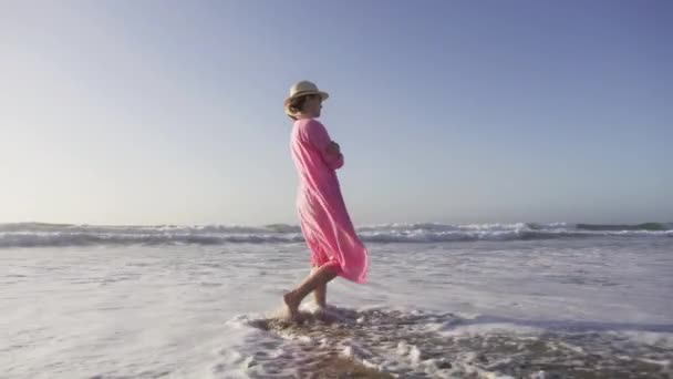 Тиха щаслива американська жінка грає з океанічними хвилями, розважаючись на пляжі на заході сонця 6K — стокове відео