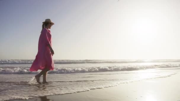 Silhouette woman in flying in wind pink dress at golden sunset in clear blue sky — ストック動画