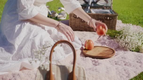 RED camera slow motion woman sitting outside on grass, eating fruits on picnic — Vídeos de Stock
