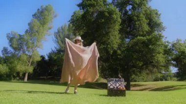 Kırmızı kamera ağır çekim kadın yaz parkında yeşil çimenlikte battaniyede dinleniyor.. 