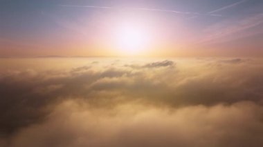 Drone is flying above scenic golden fog above ocean of rose clouds at sunrise 4K