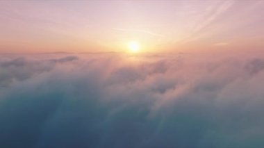 Flying through cinematic rose golden glowing cloudscape towards sunset sun 4K