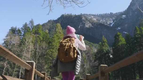 Backpacker traveler hiking in Yosemite, Back view woman walking by wooden bridge — Video Stock