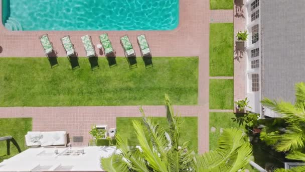 Lounge chair on terrace near bright blue swimming pool with clear rippling water — Stockvideo