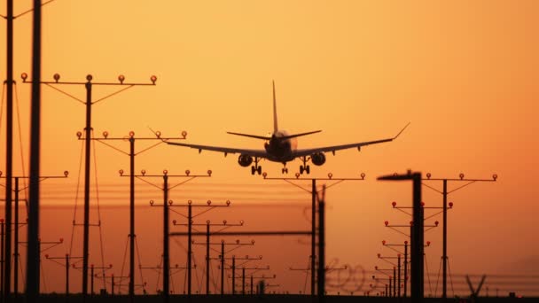 Large passenger airplane landing and flying towards scenic orange sunset RED 6K — Stock Video