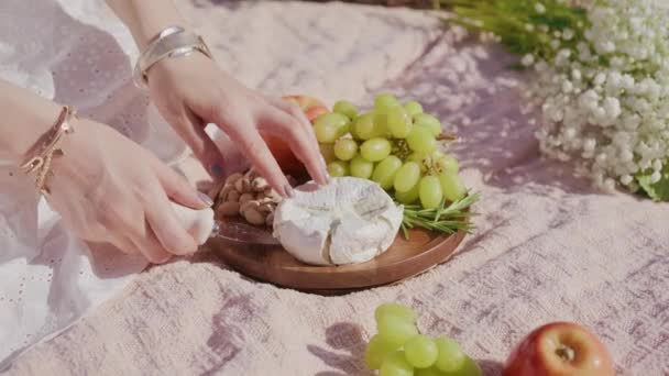Woman taking camembert brie cheese on wooden plate with grapes, apples pistachio — Vídeos de Stock