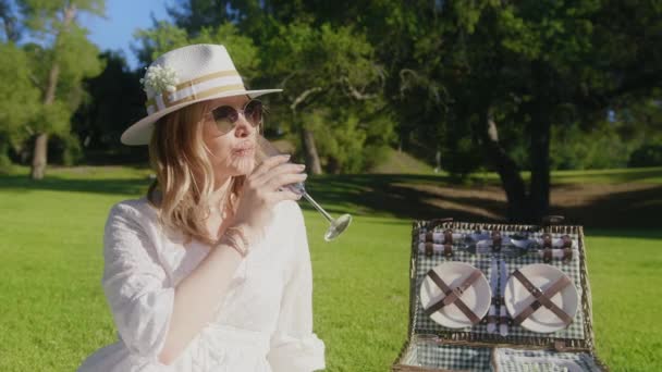 Femme en pique-nique dans un parc verdoyant, fille en lunettes de soleil jouit de champagne le jour ensoleillé — Video