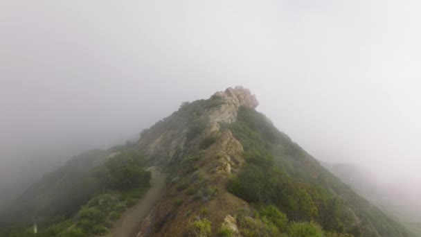 Drone voando baixo acima do cume da montanha com nuvens cobrindo em colinas verdes 4K — Vídeo de Stock