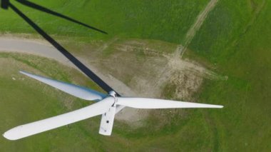 Yeşil tepelerde yenilenebilir enerji üreten yavaşça dönen yel değirmeni bıçaklarının yukarıdaki hava görüntüsünü kapatın. Çevre, sürdürülebilirlik, iklim değişikliği kavramı. Aerial 4K görüntüleri, ABD doğası