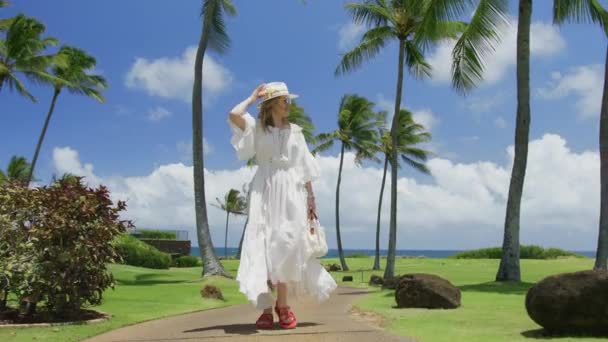 海の風の中で美しい飛行で豪華な幸せな若い女性のスローモーション白いドレスは 熱帯の島で晴れた夏の日に映画の緑のヤシの木 青い空と白い雲の背景に歩く6K — ストック動画