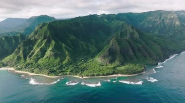 Vahşi ada doğasının sinematik yeşil dağ manzarası. Dik yeşil duvarları olan yüksek yeşil tepelerde harika derin mavi okyanus dalgaları. Manzaralı tropik Hawaii havası.