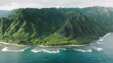 Dik yeşil duvarları olan yüksek yeşil tepelerde harika derin mavi okyanus dalgaları. Manzaralı tropikal Hawaii havası. Vahşi ada doğasının sinematik yeşil dağ manzarası