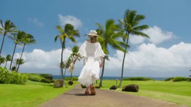 Yavaş hareket eden beyaz elbiseli kadın tropikal adada esinti elbisesi üzerinde uçuyor. Rüya gezisi, tatil seyahati konsepti RED 6K çekim. Mükemmel bir yaz günü lüks bir tatil köyünde yürüyen özgür bir kadın.
