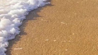 Altın kumsalın güzel deniz manzarası ve su yüzeyi dokusu, köpüklü dalgalar. Yavaş çekim güzel tropikal plaj altın ışık kırmızı görüntüsü. Sinematik beyaz deniz dalgalarıyla inanılmaz kumlu kıyı şeridi