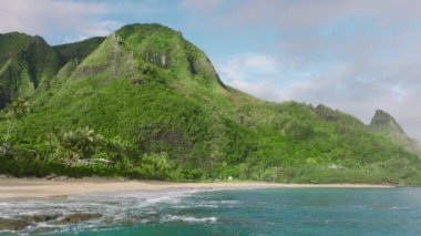 Hawaii manzaralı doğa manzarası. 4K hava aracı okyanus dalgaları üzerinde geriye doğru uçuyor. Arka planda yüksek yeşil tepeler var. Tropik ada macerası konsepti. Yaz tatili arka planı