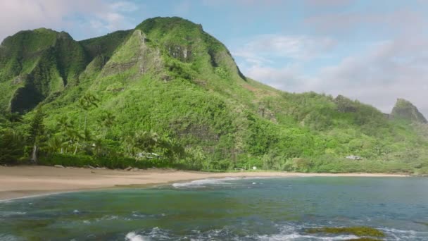 青い海の波の上を飛行する空中4Kドローンを背景にした映画のような高い緑の山 熱帯の島の冒険の概念 風光明媚なハワイの自然景観 夏休みの背景 — ストック動画