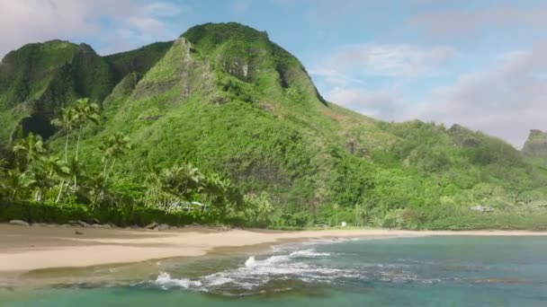 背景に美しい緑のピークの山々と海の波の上を後方に飛んで空中4Kドローン 熱帯の島の冒険の概念 風光明媚なハワイの自然景観 夏休みの背景 — ストック動画