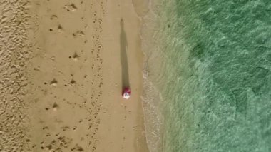 Kadın silueti gölgesi, kumlu sahilde manzaralı deniz mavisi dalgalarıyla yürüyordu. Hawaii adasında yaz tatilinde mutlu gezginler. Tropikal ada plajında 4K yavaş çekim yapan kadın.