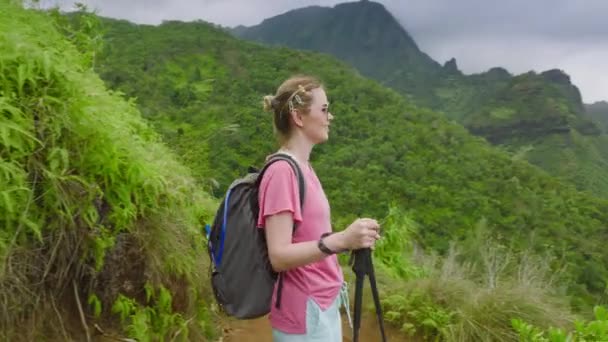 在多云的海岸背景上 妇女在青翠的热带雨林山旁远足 夏威夷考艾岛Napali海岸Kalalau小径的慢动作电影自然景观 背包客自然旅游美国 — 图库视频影像