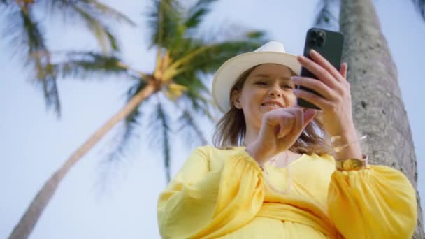 Красива Жінка Стоїть Використовуючи Смартфон Тропічному Острові Високими Зеленими Пальмами — стокове відео