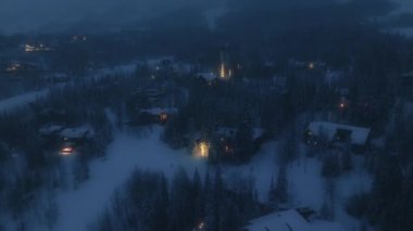 Resmedilmeye değer çevredeki büyüleyici kulübelerin havadan görünüşü. Dağlarla çevrili Alp köyünün gece manzarası. Yüksek kalite 4k görüntü