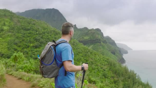 徒步旅行者站在热带丛林山边 高举双臂 手持远足手杖 适合成熟的高加索灰发男人 享受登山之旅的时光 — 图库视频影像