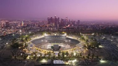 Sinema Los Angeles şehir merkezinde, pembe günbatımında. Dodgers Stadyumu gece panorama 4K hava sahasında aydınlandı. Los Angeles şehir binaları ufuk çizgisi. Dodgers Stadyumu, Los Angeles, Amerika Haziran 2022