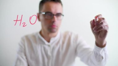 Kafkasyalı analist verileri cam bir tahtanın üzerinde gösteriyor. Gözlüklü bir bilim adamı kırmızı kalemle formüller yazıyor. Yüksek kalite 4k görüntü