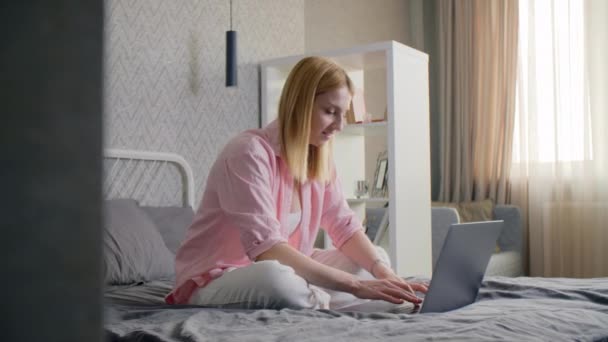 ベッドに座っている間 彼女のラップトップ上の美しい女性のタイプ 成人女性労働者は自宅で手紙を書く 高品質4K映像 — ストック動画