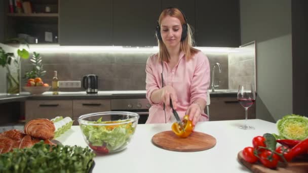 부엌에서 샐러드를 만들어요 여자가 음악을 들으면서 고추를 자르는 고품질 — 비디오