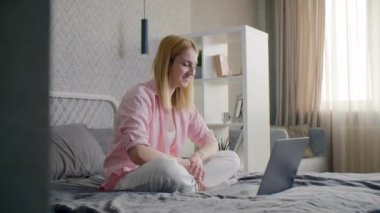 Kafkasyalı sarışın kız rahat ve şık bir odada bir yatakta oturuyor. Güzel bir kadının arkadaşlarıyla konferans görüşmesi var. Yüksek kalite 4k görüntü