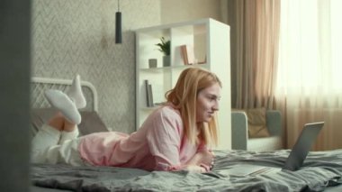 Kız, yatağında uzanırken bir video görüşmesi yapıyor. Kadın arkadaşıyla uzaktan konuşmak için dizüstü bilgisayar kullanıyor. Yüksek kalite 4k görüntü