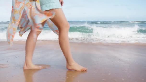 年轻女子细腿的慢动作特写走在风景优美的白色泡沫般的海浪中 拍打着水花 在她的脚之间断裂 穿着艳丽泳衣的女人在阳光下迎着海风摇曳 — 图库视频影像