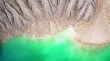 Kadın turist, arka planda kumlu tepelerle yapay taş ocağında yürüyor. Endüstriyel gölün kıyısında gezinen bir kadının havadan görünüşü. Yüksek kalite 4k görüntü