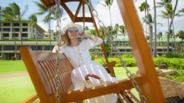 Yaz Tatili Rüya Tatili konsepti. Tropik bahçede salıncakta sallanan mutlu kadın. Çocukluk rüyası, 30 'lu yaşlardaki mutlu yetişkin kadın Hawaii' deki lüks bir adada salıncakta sallanan manken.