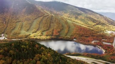 Turistler dağ gölü boyunca kırmızı turuncu sonbahar orman manzaralı sinemanın yanından geçiyorlar. 4K Echo Gölü, Cannon Dağı kayak merkezinde sonbahar günü, Franconia Notch Parkı, ABD