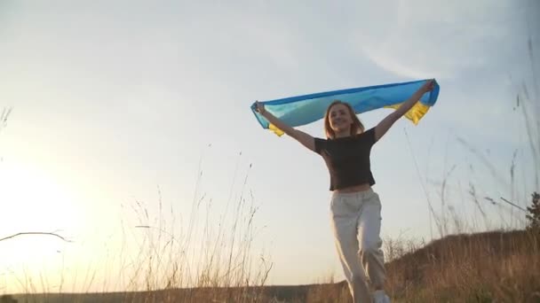ウクライナの女性は 自然の背景に彼女の頭の上のフラグで実行されています 彼女はウクライナの国旗を頭の上に掲げている スローモーション高品質のフルHd映像 — ストック動画