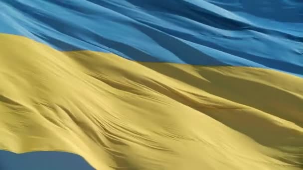 風になびく青い空の背景にウクライナの国旗を閉じます 高品質4K映像 独立国家の象徴としてのウクライナ国旗 ウクライナの国旗のサンビーム — ストック動画