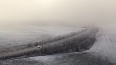 Kyiv, Ukrayna. Çorak arazi boyunca uzanan bir otoyolun havadan görünüşü. Karlı çölde beyaz bir araba sürüyordu. Yüksek kalite 4k görüntü